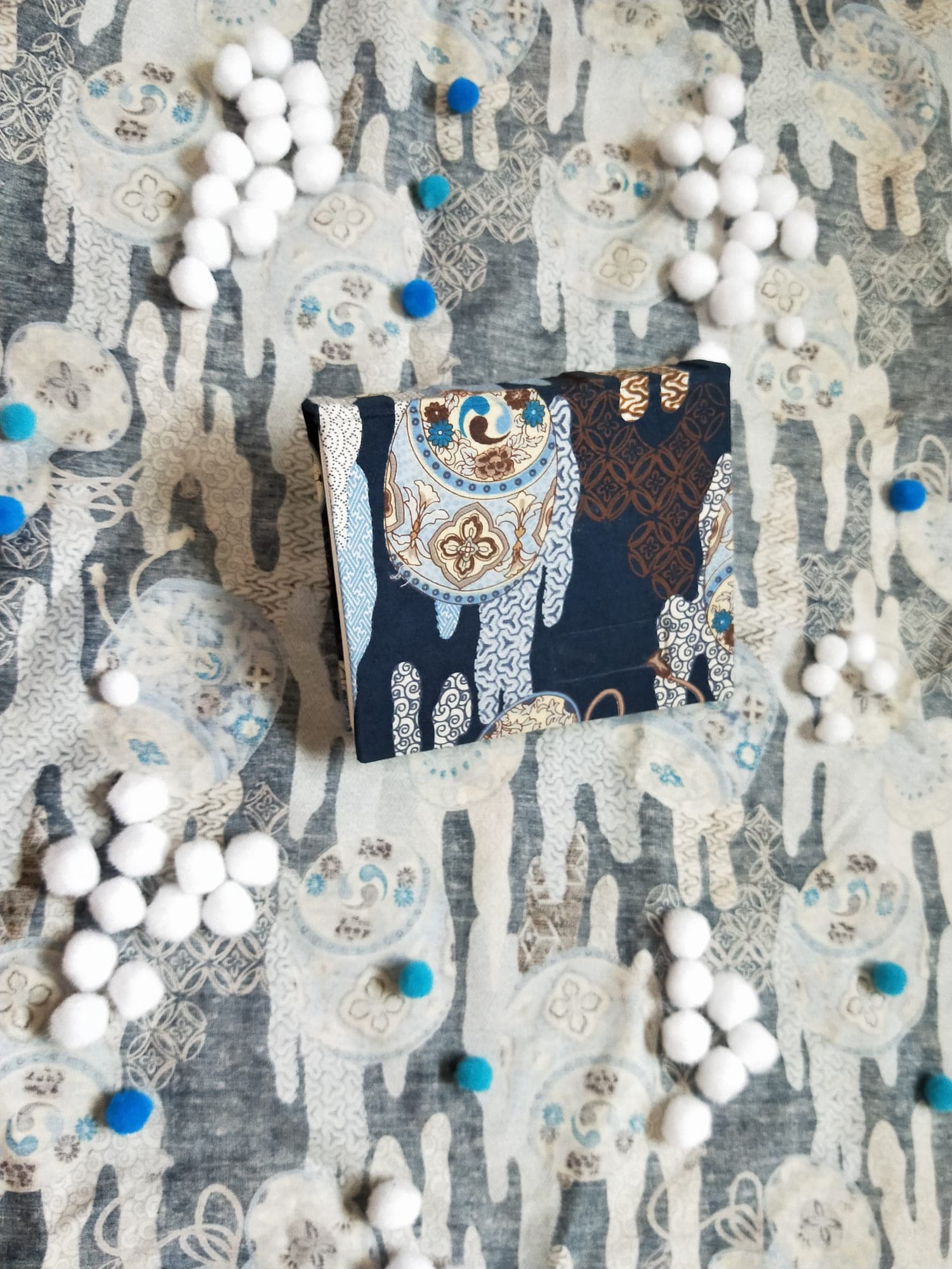 Top-down view of a closed hardcover case-bound book covered in navy Japanese-print fabric with porcelain medallion motifs.
