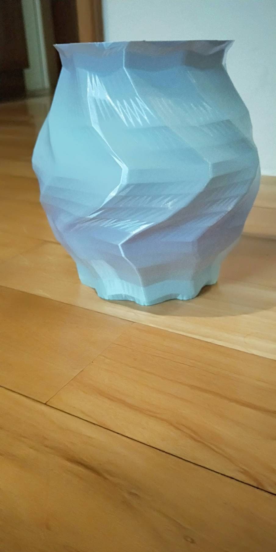 Close-up of a translucent blue and lavender low-poly 3D-printed vase, its sharp faceted ridges catching the light.