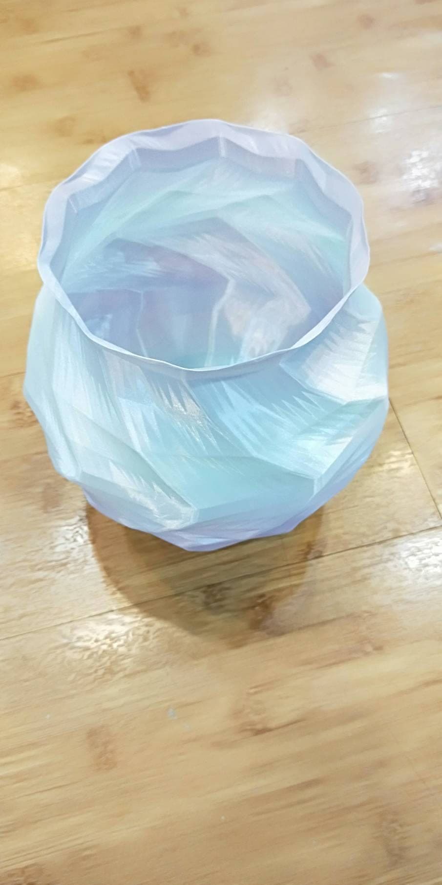 Top-down view into a translucent blue-lavender low-poly 3D-printed vase, revealing the layered facets inside the opening.